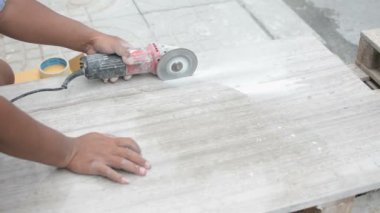 İnşaat alanındaki bir açı öğütücüyle fayans kesen bir işçi.