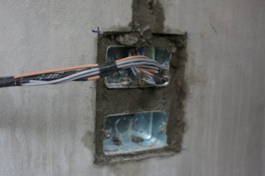 İnşaat alanındaki duvarda elektrik sistemi, demir boruları olan bir priz.