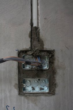 İnşaat alanındaki duvarda elektrik sistemi, demir boruları olan bir priz.