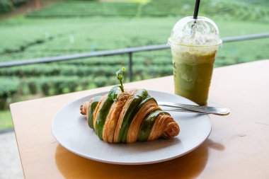 Chiang Rai bölgesindeki Choui Fong çay çiftliğinin ahşap masasında ayçöreği ile kibrit yeşili çay.