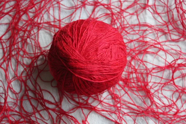 Tangled wool bright red thread, red club lying on the tangled thread.