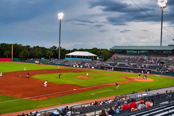 Alacakaranlıkta sahanın doğal çimlerine top fırlatan atıcı.