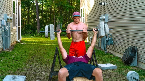 2 young athletes power lift during Corona quarantine with backyard Home built cement barbells