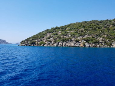 Deniz kenarındaki dağlar, sıradağlar ve kayalar, deniz manzaraları, mavi gökyüzü.
