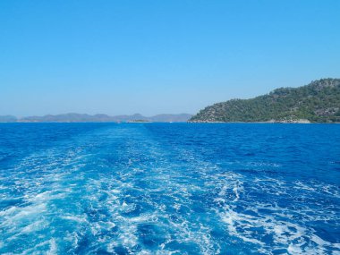 Deniz kenarındaki dağlar, sıradağlar ve kayalar, deniz manzaraları, mavi gökyüzü.