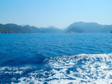Deniz kenarındaki dağlar, sıradağlar ve kayalar, deniz manzaraları, mavi gökyüzü.