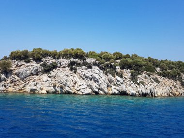 Deniz kenarındaki dağlar, sıradağlar ve kayalar, deniz manzaraları, mavi gökyüzü.
