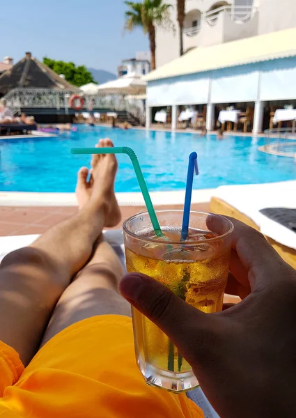 Havuz kenarında dinlenmek, soğuk taze kokteyl, otelde dinlenmek, turizm, havuz başındaki adamın bacakları.