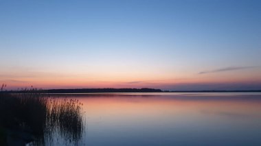 Gölün üzerinde güzel bir gün batımı, suyun üzerinde yansıma.