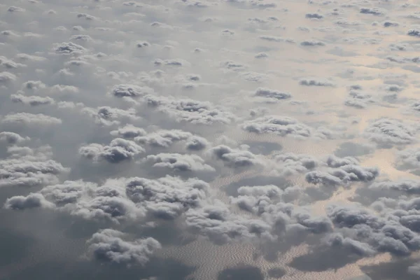 Mavi okyanusun üzerinde beyaz bulutlar, uçak penceresinden manzara