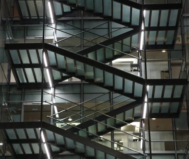 Parlak ışık ve arka planla aydınlatılmış büyük bir binanın merdivenleri.