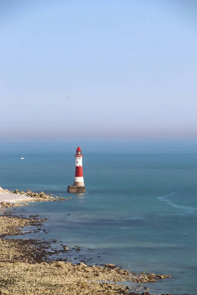 white and red lighthouse in the oceans and blue sky