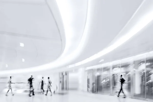 背景がぼやけている現代のビジネスセンターのロビーにいる人々の抽象的なイメージです — ストック写真