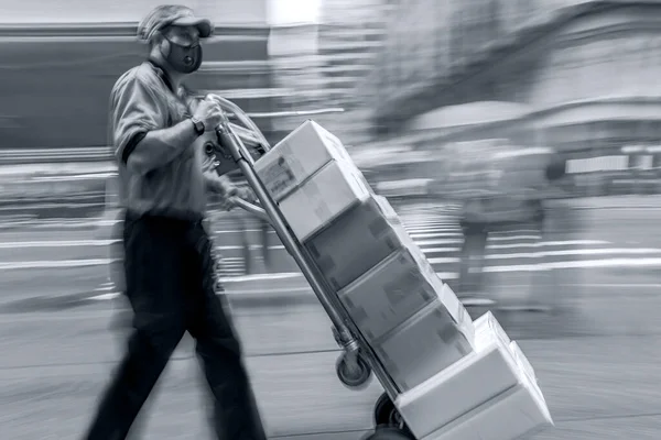 masked business people in a city, delivery goods with dolly by hand, purposely motion blur