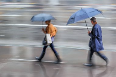 Yağmurlu bir günde sokakta yürüyen iş adamları bulanıklaştı