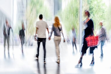 Bulanık bir geçmişi olan modern bir iş merkezinin lobisindeki insanların soyut görüntüleri.