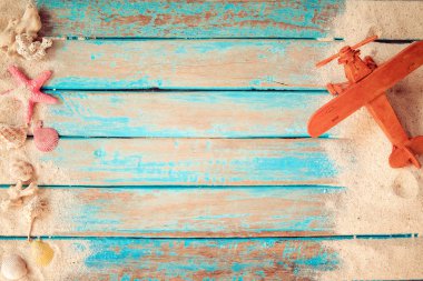 Bir tatil ve yaz kavramı - plaj kum ve oyuncak hava uçak en iyi görünümünü mavi deniz boya arka planda ahşap tahta üzerinde seyahat. 