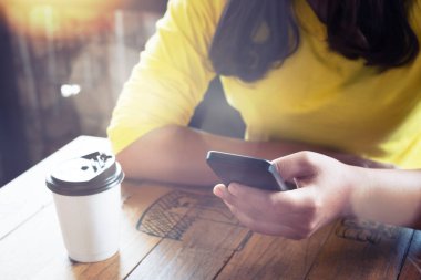 Eller kadın bir kafede tahta masada oturan akıllı telefonu kullanma. Asyalı kadınlar bir kafede - film renk tonu oturup rahatla.