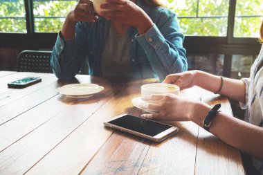 Arkadaşları ile akıllı telefon kafede çalışan iş ekip çalışması genç kadınlar. Toplantı ve ara zaman kavramı. Yeni başlangıç online pazarlama projesi. Vintage film etkisi