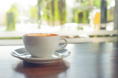 Beyaz fincan sıcak kahve ile sabah ışığı, retro vintage renk tonlu kafede masada.