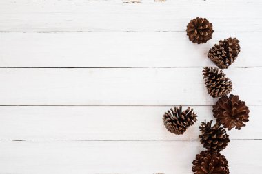 Noel rustik arka plan beyaz ahşap üzerine çam kozalağı ile. en az tarzı, üstten görünüm, sınır.