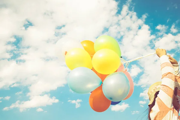 Girl hand holding multicolor balloons done with a retro instagram filter effect, concept of happy birth day in summer and wedding honeymoon party, Vintage color tone style