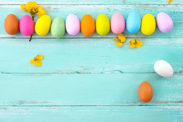 Çiçek rustik ahşap plakalar arka planda mavi boya ile renkli Paskalya yumurtaları. Bahar mevsimi tatil. Vintage pastel renk tonu. Üstten Görünüm kompozisyon.