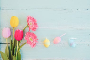Lale çiçek rustik ahşap plakalar arka plan üzerinde renkli Paskalya yumurta. Bahar mevsimi tatil. Vintage pastel renk tonu. Üstten Görünüm kompozisyon.