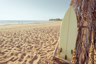 Kumsallar sakin deniz ve gökyüzü arka plan ile kum tropikal plaj üzerinde Surfboard. yaz tatili arka plan ve su spor kavramı. Vintage renk tonu efekti.