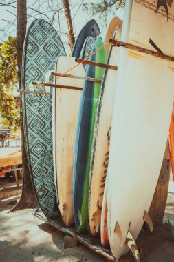 Bir yığın sahilde Kiralık kullanılabilir farklı renkli surf kurulları kümesi. Dikey sörf tahtaları, vintage renk tonu efekti.