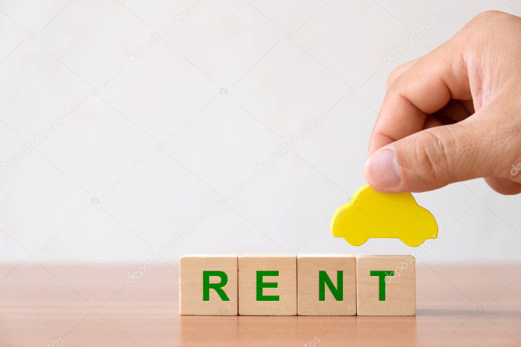 Vehicle, transportion investment and car mortgage financial concept. Hands holding wooden car and wood cube block with RENT word. 