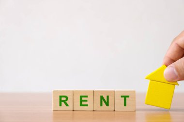 Mülkiyet yatırım ve ev mortgage finansal kavramı. Kiralık kelime ile ahşap ev ve ahşap küp blok tutan eller.