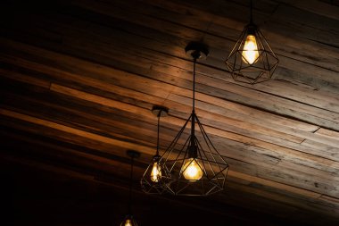 Çatı katı ve köy tarzında bir ev. Karanlıkta parlayan kaliteli, lüks bir ampul asılı. Retro filtre efekt biçimi. Tarihin ve modern hayatın karışımı.