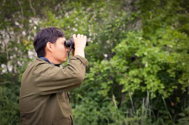Dürbünlü bir erkek avcı, avını ormanın arka planına doğru gözetler. Bir avcı kavramı, başarılı ya da başarısız avı. Görüntü.