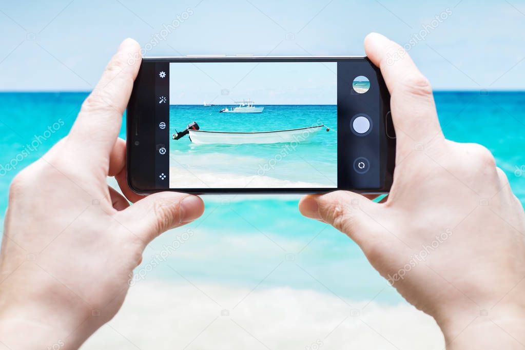 Tourist taking a picture of the boat in the Sea