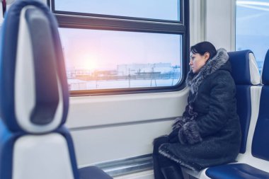 Genç güzel kız tren sürmek ve kış günbatımında pencereden görünüyor