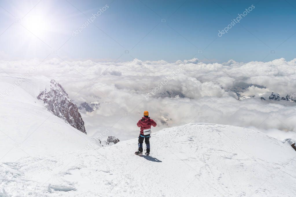 The climber stands on the top of Elbrus and looks ahead. Russia, Caucasus.
