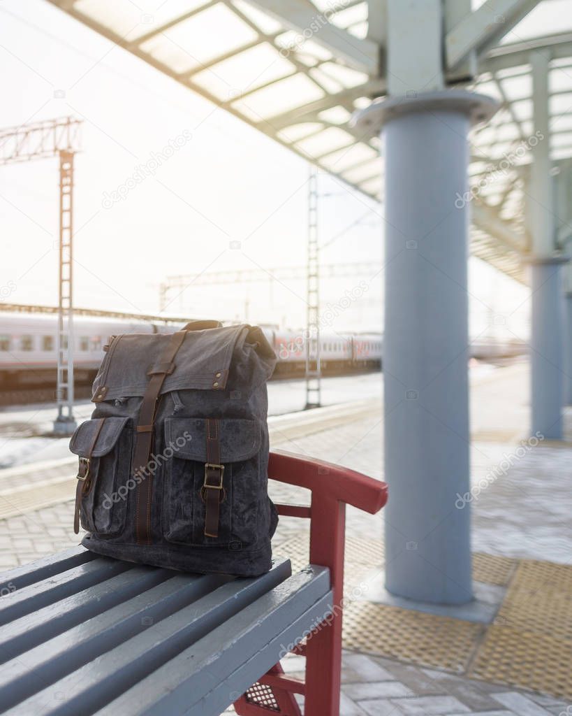 Stylish vintage backpack of waxed material at the railway station. Travel concept.