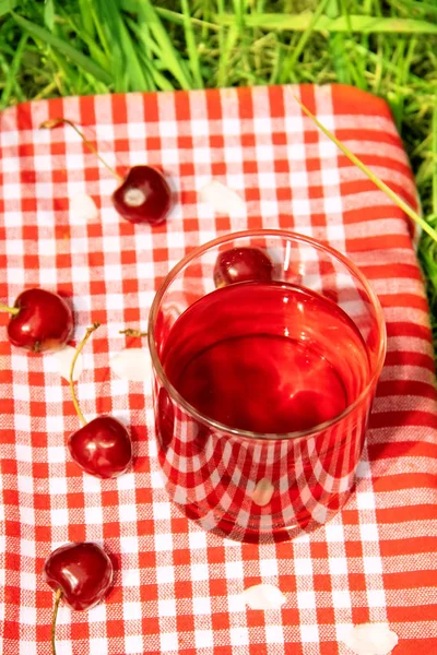 Cherry juice. Summer picnic. Juice on a checkered tablecloth