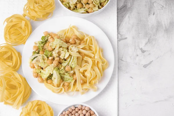 Vegetarian pasta dinner with lettuce and chickpeas on a gray background. Copy space. Healthy eating