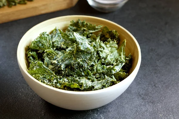 kale chips in bowl on black background