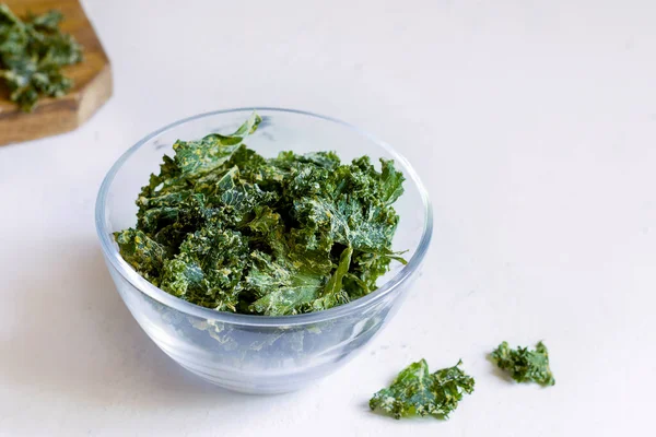 Kale chips in een glazen schaal op een witte achtergrond. kopieerruimte — Stockfoto