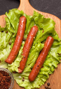 Vejetaryen eti konsepti. Marulun üzerindeki sosisler, ahşap mutfak tahtasının üzerinde yakın plan..