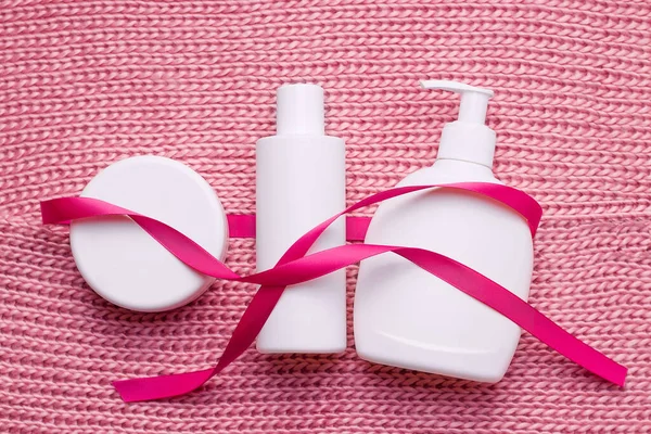 Concept of a gift set of cosmetics for christmas. Bottles white on pink scarf texture — Stock Photo, Image