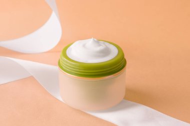 Bej bir arka planda kavanozda yüz kremi.
