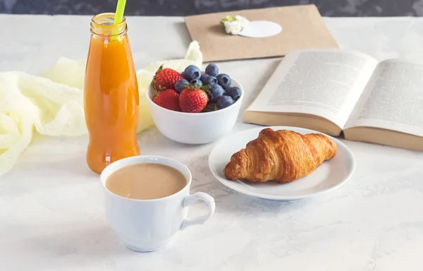 Сніданок з круасанами, ягодами і книга на білому тлі — стокове фото