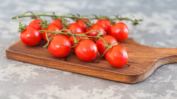 Rama de tomates cherry frescos y albahaca sobre tabla de madera — Foto de Stock