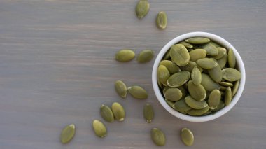 Ahşap arka plan üst görünümü üzerinde beyaz kase kabak tohumları