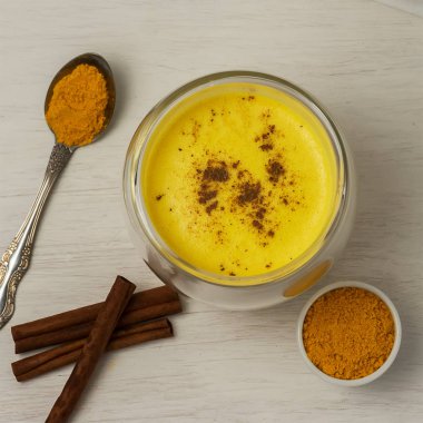 Beyaz ahşap arka plan üzerinde baharat ile zerdeçal süt. Sağlıklı içecek. Üstte görüntü