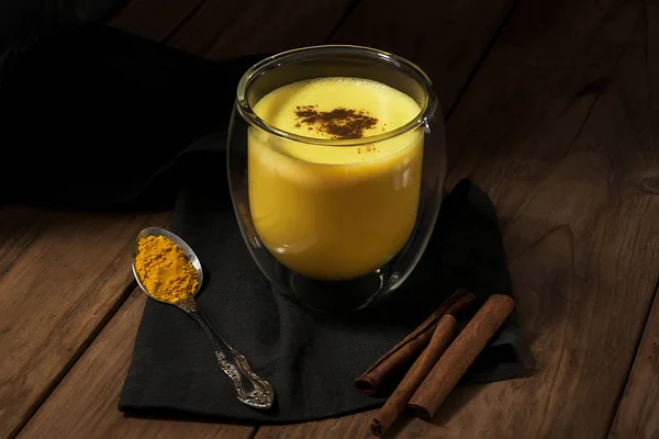 Minuman tradisional India. Latte emas, susu kunyit dengan rempah-rempah pada latar belakang kayu gelap — Stok Foto